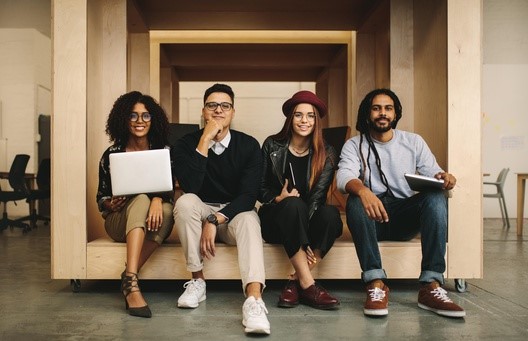 Grupo de jovens em ambiente de interação em escritório, ilustram publicação com lista de vagas abertas na PUC Carreiras.