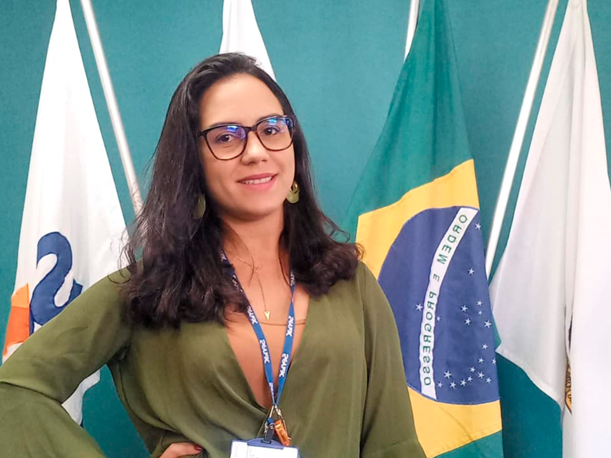 Aluna Emanuely Mota em pé, com bandeiras ao fundo