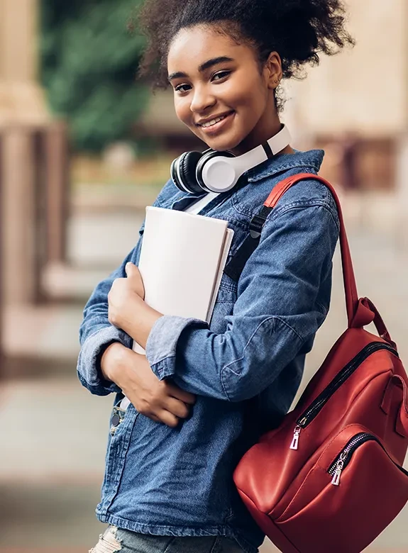 Jovem negra com caderno e mochila em ambiente externo