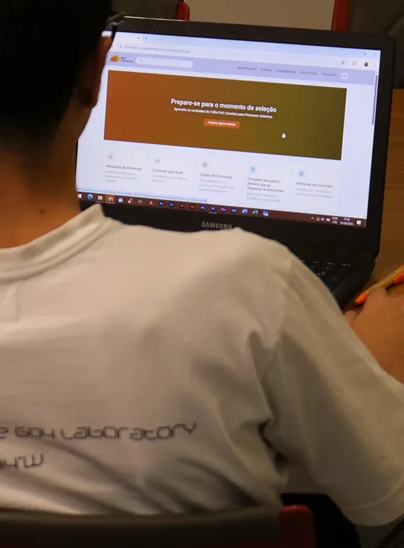 Aluno olhando para tela da Plataforma PUC Carreiras em notebook