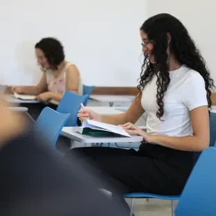 Aluna lendo livro em sala de aula da Universidade